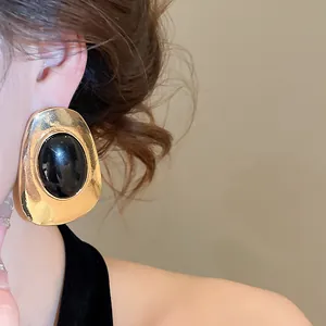 Detail view of a large vintage gold-tone oval earring featuring a black domed resin center