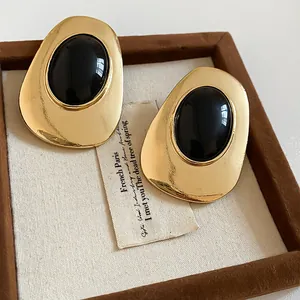 Close-up of vintage gold oval earrings with black resin inlay on display box