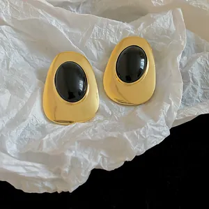 Detailed view of vintage-style gold oval earrings featuring a polished black resin center