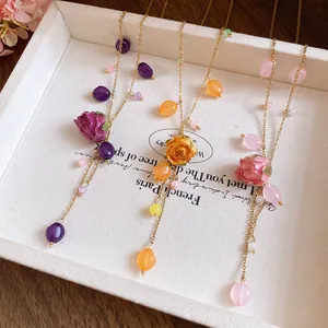 Detailed macro view of preserved rose pendants on stainless steel tassel necklaces