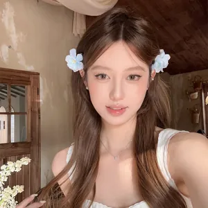 Barrettes à fleurs en tissu bleu et blanc portées par un mannequin pour un look de vacances