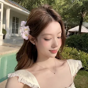 Gros plan d'une pince à cheveux en fleur rose portée par un mannequin en extérieur chic