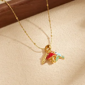 Detailansicht der Anhänger mit einem roten Pilz und einem blauen Vogel an einer Goldkette