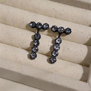 Elegant T-shaped black stud earrings with sparkling zircon stones on a jewelry tray.