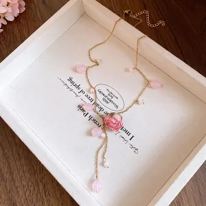Close-up of pink resin rose and bead tassel on a gold stainless steel necklace.