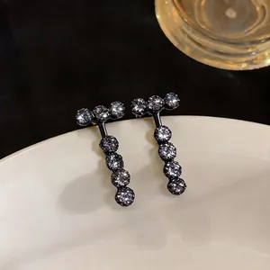 Black plated T-shaped stud earrings featuring sparkling round zircons on a white plate