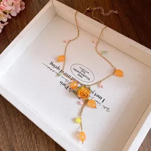 Detail view of handmade resin necklace with preserved orange rose and beads