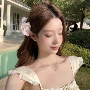 Gros plan d'une grande pince à cheveux en forme de fleur rose portée par un modèle