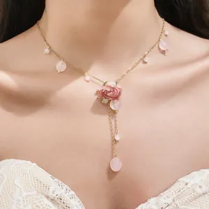 Close-up view of a pink resin rose necklace with delicate tassel beads on an elegant model