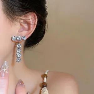 Close-up of elegant zircon round drop earrings worn on an Asian model for fashion.