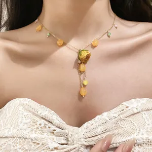 Detail of a preserved yellow rose necklace with resin tassels worn on a model's neck