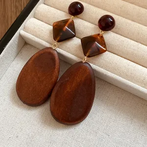 Detailed shot of vintage wood teardrop earrings featuring brown amber resin accents.