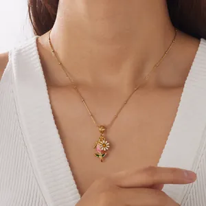Detailaufnahme einer vergoldeten Halskette mit Blumen- und Pfirsichanhänger auf Weiß.