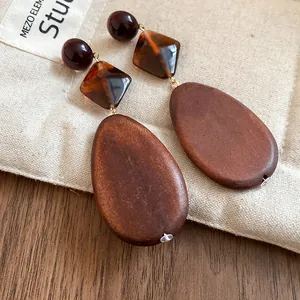 Close-up of vintage brown wooden teardrop earrings with amber acrylic diamond beads
