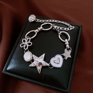 Gros plan d'un bracelet punk argenté avec des breloques étoile et cœur en strass sur écrin