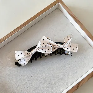 Nahaufnahme einer eleganten Haarklammer mit cremefarbener gepunkteter Schleife