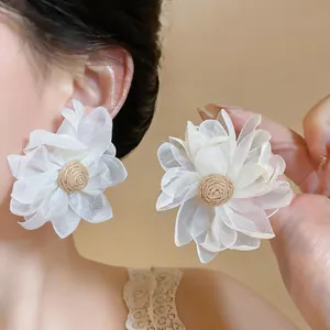 Macro detail of the elegant white mesh flower earring featuring a woven raffia center