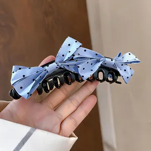 Detailaufnahme einer hellblauen Haarklammer mit gepunkteter Schleife und schwarzer Basis.