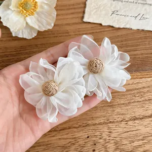 Detailed view of cream white mesh flower earrings featuring hand-woven raffia centers.