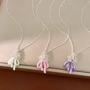 Dettaglio di collane con fiocco e fiori in zircone in smalto verde, rosa e viola.