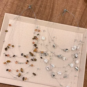 Elegante collana multistrato con perle irregolari e perline d'argento su fili sottili.