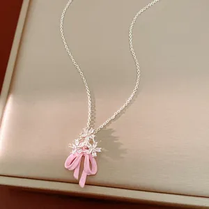 Primo piano della collana con ciondolo a fiocco rosa in smalto e fiori in zirconi.