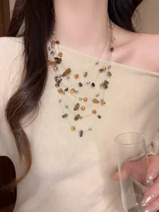 Dettaglio di una collana a più strati con perle irregolari in ambra e occhio di tigre