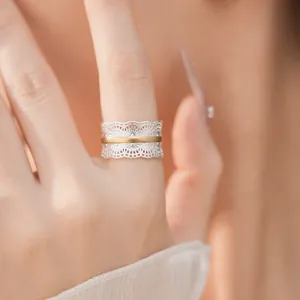 Primo piano di un elegante anello traforato bicolore con dettagli in pizzo sul dito