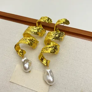 Close-up of vintage hammered gold spiral earrings with large baroque pearl drops