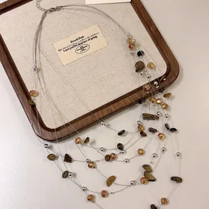 Dettaglio ravvicinato di collana multistrato con pietre occhio di tigre e cristalli