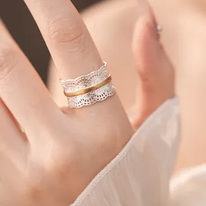 Primo piano di elegante anello aperto in pizzo traforato con finitura bicolore