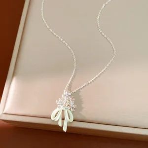 Primo piano del ciondolo con fiori in zircone e fiocco in smalto verde chiaro