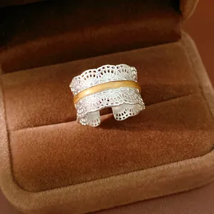 Vista dettagliata di un anello in pizzo d'argento con fascia dorata in una scatola regalo