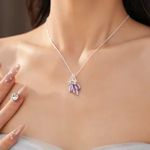 Primo piano dell'elegante ciondolo con fiocco in smalto viola e dettagli di fiori in zircone