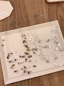 Dettaglio di collane multistrato con perle bianche irregolari e pietre marroni naturali
