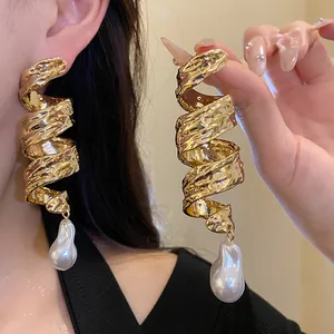 Detailed view of retro golden spiral twisted earrings with large baroque pearl drops