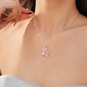 Dettaglio ravvicinato di una collana in argento con fiori di zircone e fiocco in smalto rosa.