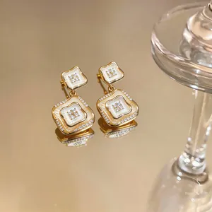 Vista detallada de pendientes dorados con nácar y circonitas, estilo vintage francés