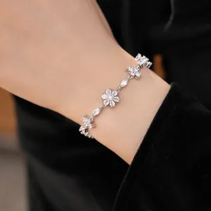 Detailed view of vintage flower and cross bracelet with shimmering zirconia stones.