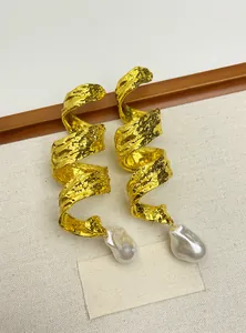 Macro detail of vintage gold spiral crinkled metal earrings with white baroque pearl drops