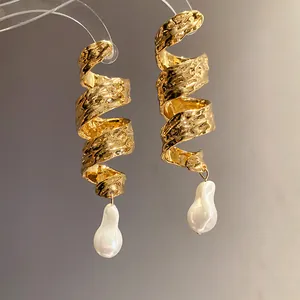 Detailed view of vintage gold hammered spiral earrings with baroque pearl drops