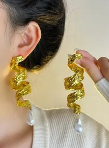 Close-up of vintage gold spiral drop earrings with oversized baroque pearls on model