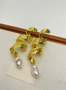 Close-up detail view of vintage spiral gold earrings featuring irregular baroque pearls.