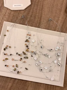 Dettaglio di collana multifilo elegante con perle irregolari e perline su vassoio.