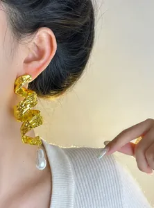 Close-up of vintage gold spiral wrap earrings with a baroque pearl drop detail