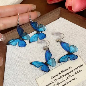 Detailed view of blue resin butterfly earrings with translucent wings and silver clips