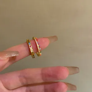 Macro close-up detail of two ultra-thin gold stackable rings with colorful zircons