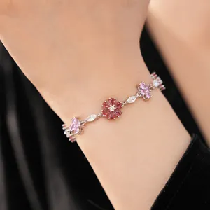 Close-up detail of a vintage silver bracelet with pink zircon flowers on a female wrist.
