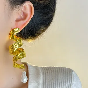 Detailed shot of vintage gold spiral earrings with a baroque pearl pendant on a model