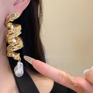 Macro view of luxurious retro gold spiral earrings featuring a baroque pearl drop detail